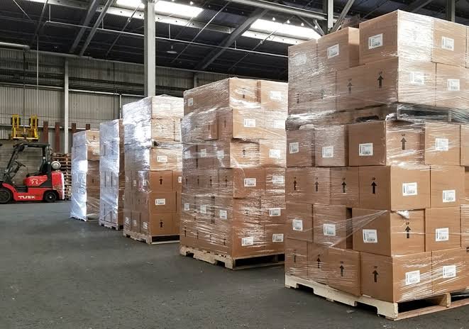 Palletized, shrink-wrapped freight staged in a warehouse with a forklift